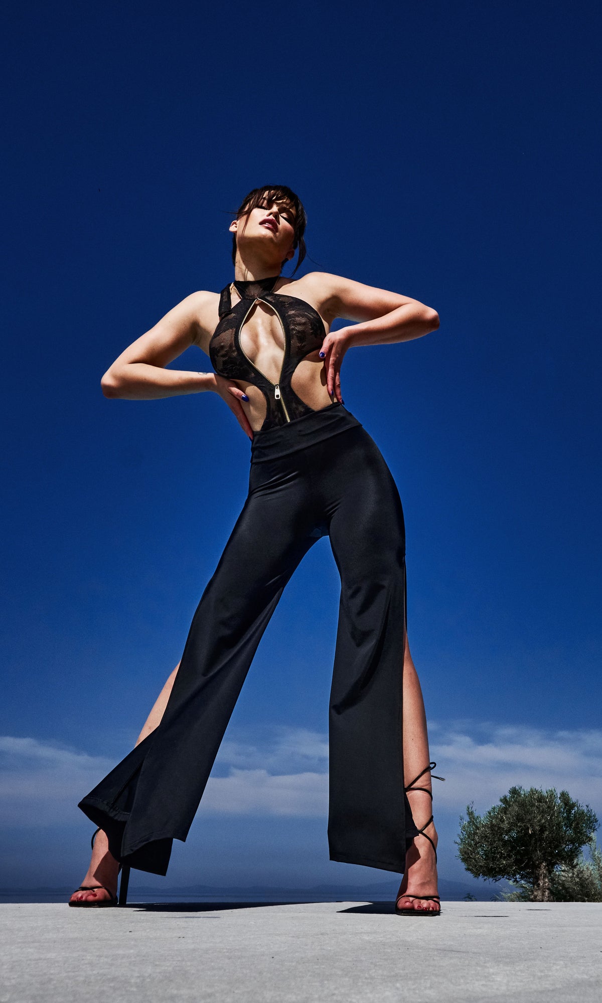 Model wearing Flora luxury sustainable one-piece swimsuit by Antoninias, featuring lace paneling, front zipper, and cut-out details, perfect for premium designer resort wear.