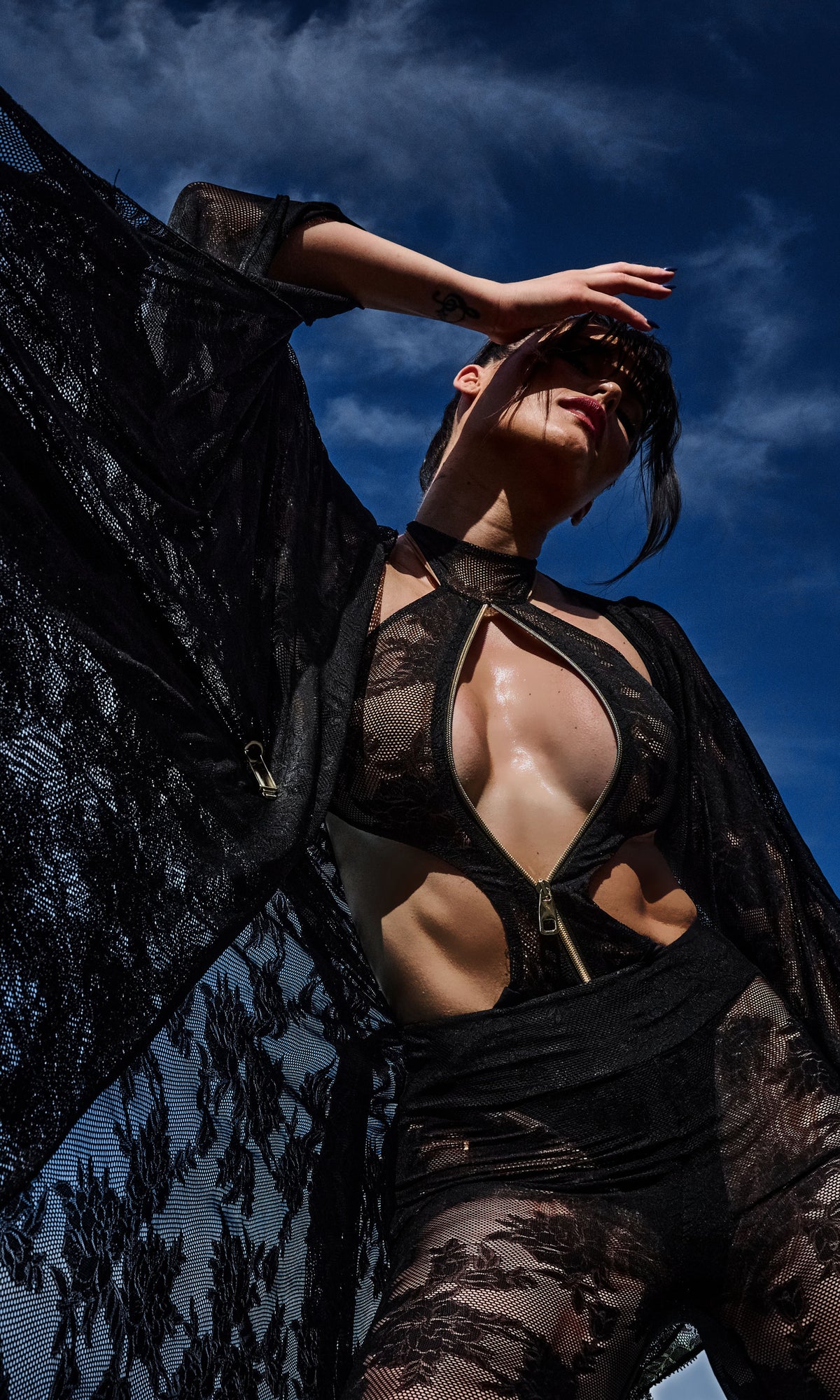 Model wearing Flora luxury sustainable one-piece swimsuit by Antoninias, featuring lace paneling, front zipper, and cut-out details, perfect for premium designer resort wear.